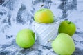 A group of green Granny Smith and golden apples in a white bucket against a white concrete background, copy space for text Royalty Free Stock Photo