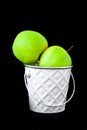 A group of green Granny Smith and golden apples in a white bucket against a dark brown background, copy space for text Royalty Free Stock Photo