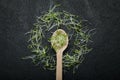 Group of green sprouts, micro greens, baby vegetables on a black background in the shape of a circle around a wooden spoon