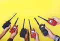 Group of hands holding portable two way radios with yellow background Royalty Free Stock Photo