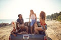 A group of handsome models is spending wonderful time in the back of a car at sea. Summer, sea, vacation, friendship