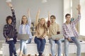 Group of happy active school or college students sitting on desk and raising hands Royalty Free Stock Photo