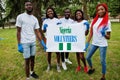 Group of happy african volunteers hold blank with Nigeria flag in park. Africa countries volunteering, charity, people and ecology