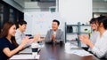 Group of happy Asian business people discuss together in team brainstorm meeting and clap hand, work late night in office