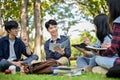 Group of a happy Asian college students sitting in the campus`s park, enjoy talking together Royalty Free Stock Photo