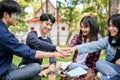 A group of happy Asian college students sitting in the park, putting their hands together, cheering up Royalty Free Stock Photo