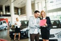 Group of happy car sales consultants working inside vehicle showroom Royalty Free Stock Photo