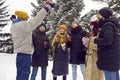 Group of happy young men and women drinking coffee and having fun in winter park Royalty Free Stock Photo