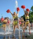 Group of happy Cheerleaders enjoy jogging through the fountain