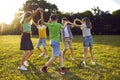 Group of happy children dancing in a circle while playing together in the park in summer Royalty Free Stock Photo