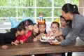 group of happy children girl with hat blowing candles on  birthday cake together celebrating in  party . kids gathered around Royalty Free Stock Photo