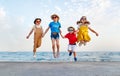 Group of happy children jump by sea in summer