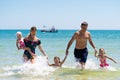 Group of happy children playing and splashing in the sea beach. Kids having fun outdoors. Summer vacation and healthy Royalty Free Stock Photo