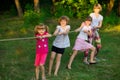 Group of happy children playing tug of war outside on grass. Kids pulling rope at park Royalty Free Stock Photo