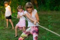 Group of happy children playing tug of war outside on grass. Kids pulling rope at park Royalty Free Stock Photo