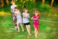 Group of happy children playing tug of war outside on grass. Kids pulling rope at park. Royalty Free Stock Photo