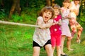 Group of happy children playing tug of war outside on grass. Kids pulling rope at park. Summer camp Royalty Free Stock Photo