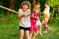 Group of happy children playing tug of war outside on grass. Kids pulling rope at park. Summer camp Royalty Free Stock Photo