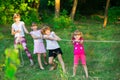 Group of happy children playing tug of war outside on grass. Kids pulling rope at park Royalty Free Stock Photo