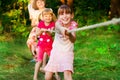 Group of happy children playing tug of war outside on grass. Kids pulling rope at park. Summer camp Royalty Free Stock Photo