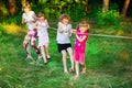 Group of happy children playing tug of war outside on grass. Kids pulling rope at park. Summer camp Royalty Free Stock Photo