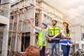 Group of happy contractors, engineers and formats in safety vests with helmets stand on the under-construction building site. Royalty Free Stock Photo