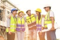 Group of happy contractors, engineers and formats in safety vests with helmets stand on the under-construction building site. Royalty Free Stock Photo