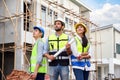 Group of happy contractors, engineers and formats in safety vests with helmets stand on the under-construction building site. Royalty Free Stock Photo