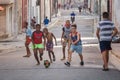 several children playing ball in the middle of an alleyway in cuba