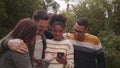 Group of happy diverse friends standing together taking selfie on smartphone in the park