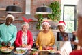 Group of happy diverse senior male and female friends in christmas hats taking selfie in kitchen Royalty Free Stock Photo