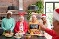 Group of happy diverse senior male and female friends in christmas hats taking selfie in kitchen Royalty Free Stock Photo