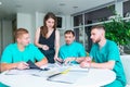 Group of happy doctors or interns with mentor meeting and taking notes at hospital. medical education, health care, people and Royalty Free Stock Photo