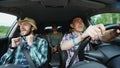 Group of happy friends in car singing and dancing while drive road trip