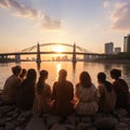 Group of happy friends chatting in front of the sunset with their backs to the camera. Travel, people, leisure and teenager.