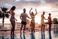 Group of happy friends dancing at pool party at sunset - Young millennial people having fun in a tropical luxury resort Royalty Free Stock Photo