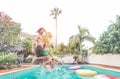 Group of happy friends drinking jumping in pool at sunset party - Young diverse culture people having fun in tropical vacation - Royalty Free Stock Photo