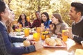 Group of happy friends eat and laugh at a table at a barbecue