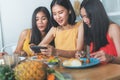 Group of happy friends eating dinner together and shel taking photo of food on the table