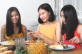 Group of happy friends eating dinner together and she taking photo of food on the table