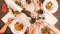 Group of happy friends eating and drinking pasta, pizza and wine - people having meal in restaurant - Focus on wine glasses - Royalty Free Stock Photo