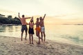 Group of happy friends enjoying beautiful sunset at the tropical beach, jumping and having fun together. Travelers Royalty Free Stock Photo