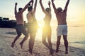 Group of happy friends enjoying beautiful sunset at the tropical beach, jumping and having fun together. Travelers Royalty Free Stock Photo