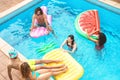 Group happy friends enjoying summer day in swimming pool with inflatable - Young multiracial people having fun in exclusive resort Royalty Free Stock Photo