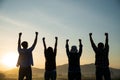 Group of happy friends are having fun with raised arms together in front of mountain and enjoy sunrise sunset showing unity and Royalty Free Stock Photo