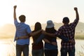 Group of happy friends are having fun with raised arms together in front of mountain and enjoy sunrise sunset showing unity and Royalty Free Stock Photo