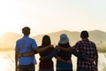 Group of happy friends are having fun with raised arms together in front of mountain and enjoy sunrise sunset showing unity and