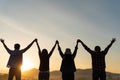 Group of happy friends are having fun with raised arms together in front of mountain and enjoy sunrise sunset showing unity and