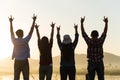 Group of happy friends are having fun with raised arms together in front of mountain and enjoy sunrise sunset showing unity and Royalty Free Stock Photo