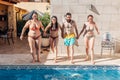 Group of happy friends holding hands and jumping in pool. Young diverse culture people having fun in vacation. Holiday, youth and Royalty Free Stock Photo